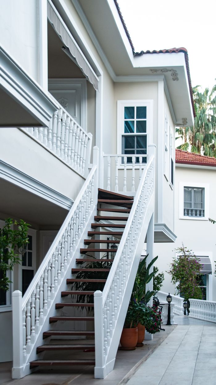 our-experience Stylish white staircase outside a contemporary villa with lush greenery and elegant design.