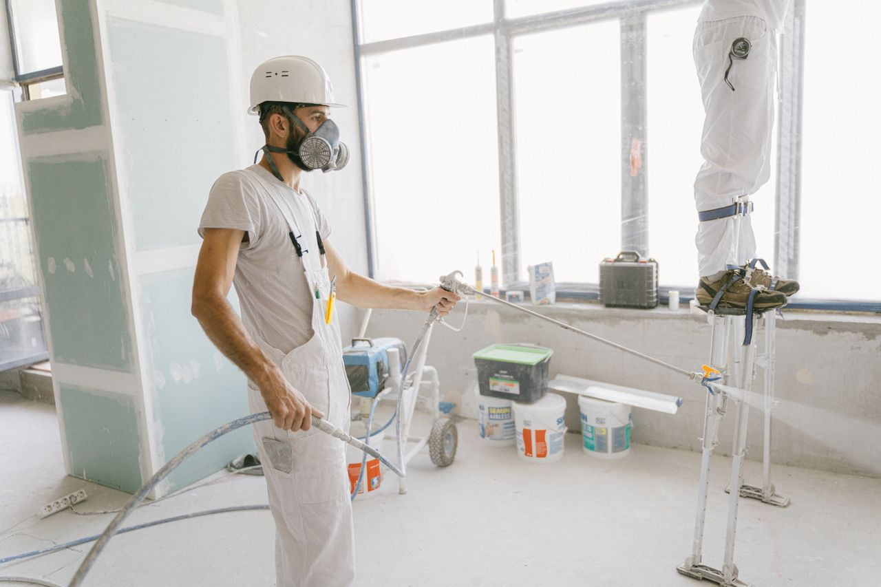 Crafting Captivating Headlines: Your awesome post title goes here Two construction workers wearing protective gear and painting interior walls for a renovation project.